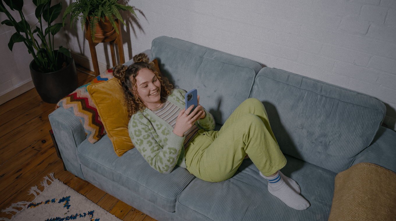 Monefit cardholder relaxing on the couch while checking her phone
