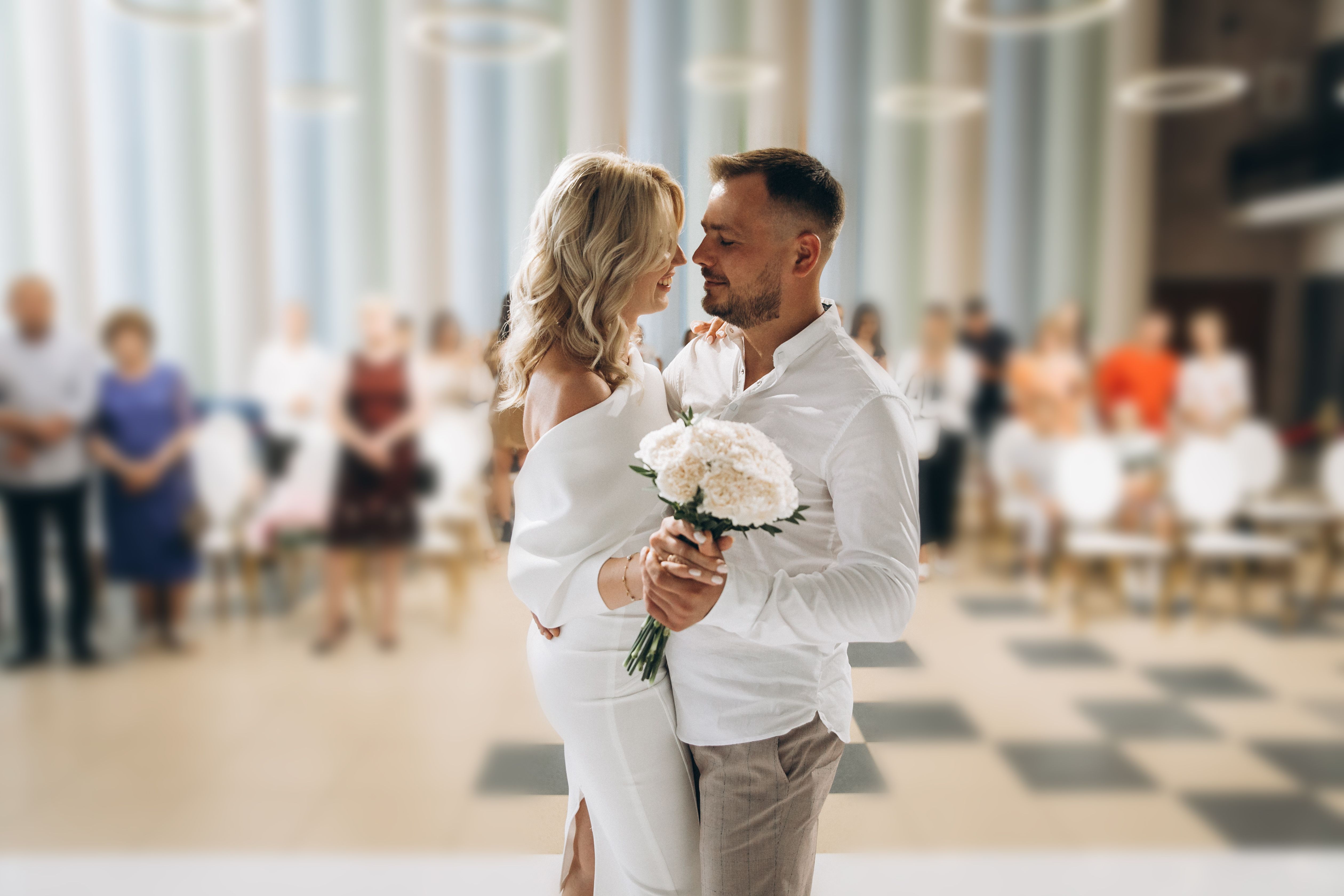 romantic-wedding-ceremony-couple-embracing-with-guests-background.jpg