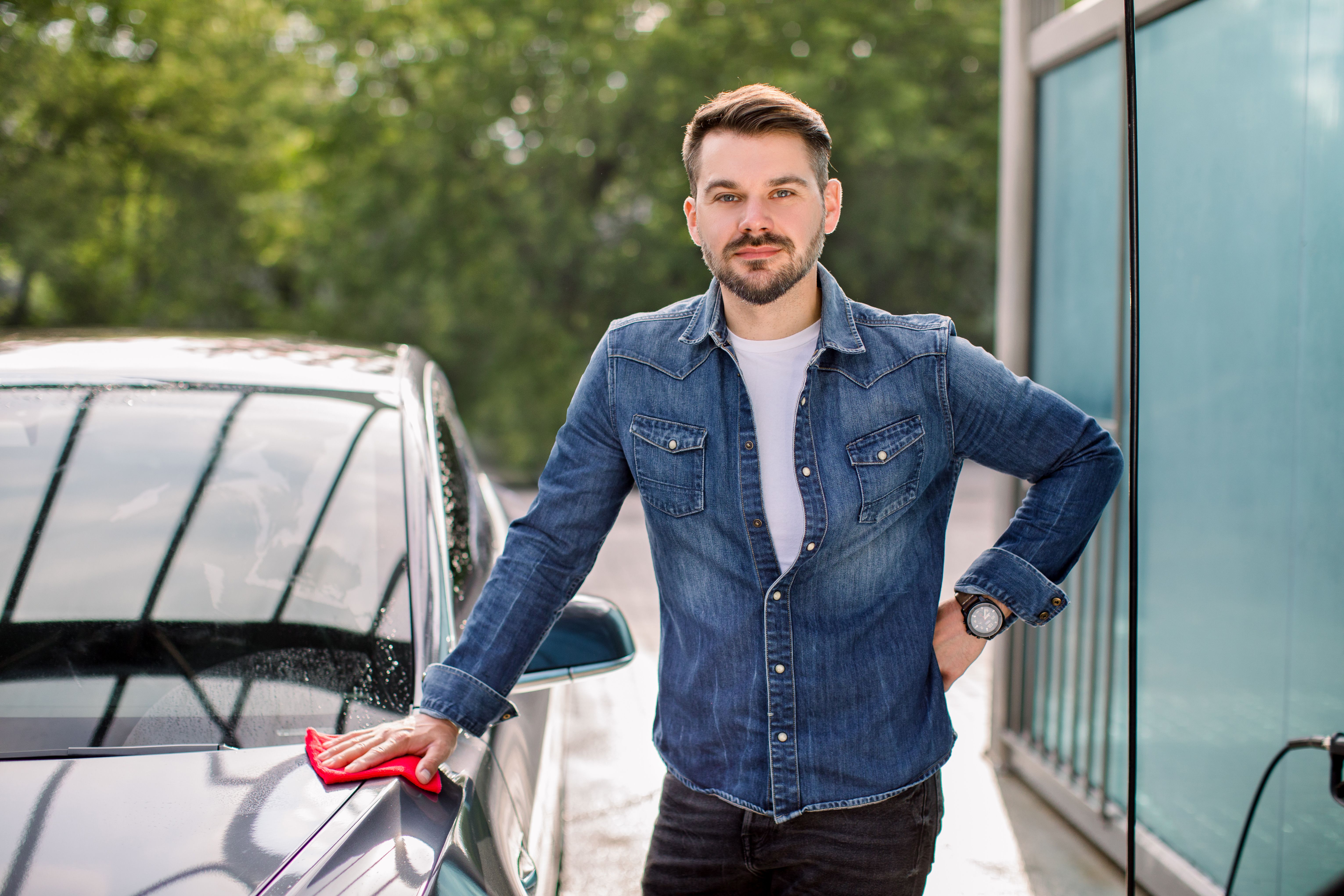 young-handsome-bearded-smiling-caucasian-man-casual-jeans-shirt-standing-near-his-new-luxury-car-outdoor-self-service-car-wash-station.jpg
